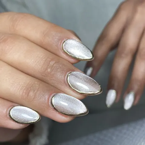 Uñas con efecto ojo de gato plateado y borde dorado